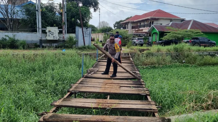 Bhabinkamtibmas dan Warga Gotong Royong Perbaiki Jembatan