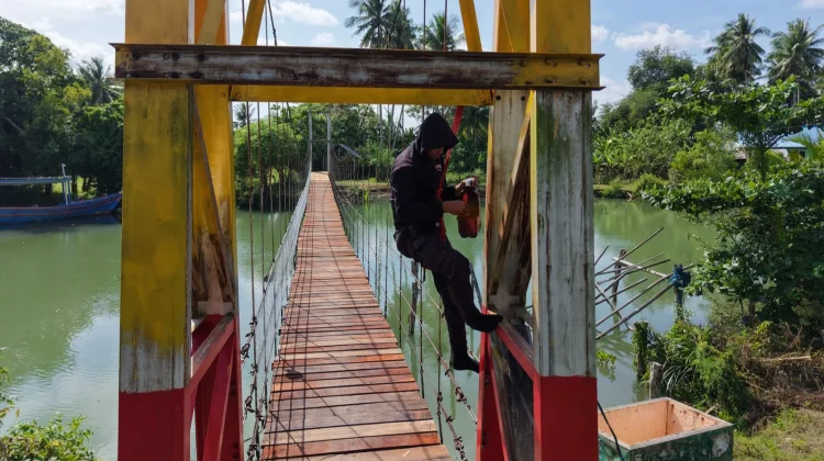 Brimob Lanjutkan Pengecatan Jembatan Gantung Desa Kading Bone