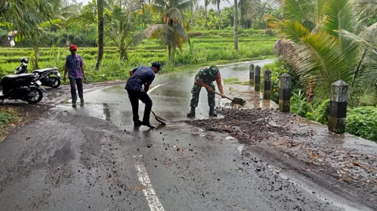 Babinsa Semarapura Kaja Bersihkan Pasir dan Koral Jalan Raya