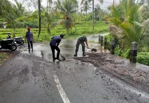 Babinsa Semarapura Kaja Bersihkan Pasir dan Koral Jalan Raya