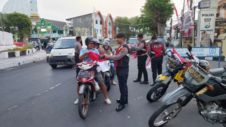 Personil Polres Lumajang Berbagi Bendera Merah Putih Kepada Pengendara