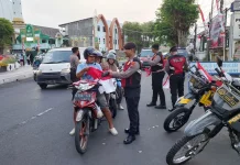 Personil Polres Lumajang Berbagi Bendera Merah Putih Kepada Pengendara