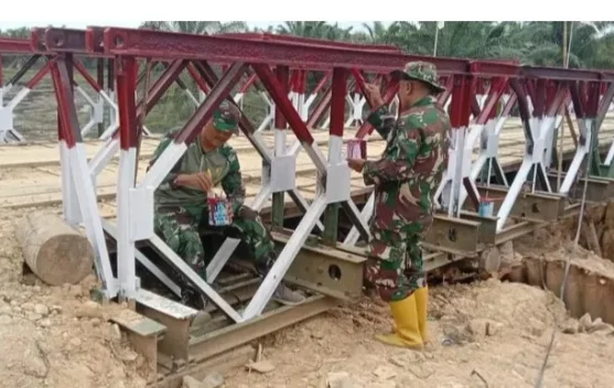 Anggota Koramil 13/Baktiya Lanjutkan Pengecatan Jembatan Belly