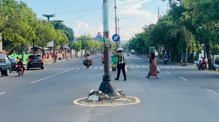Personel Satlantas Polresta Sumenep Membantu Warga Menyeberang di Area Pasar
